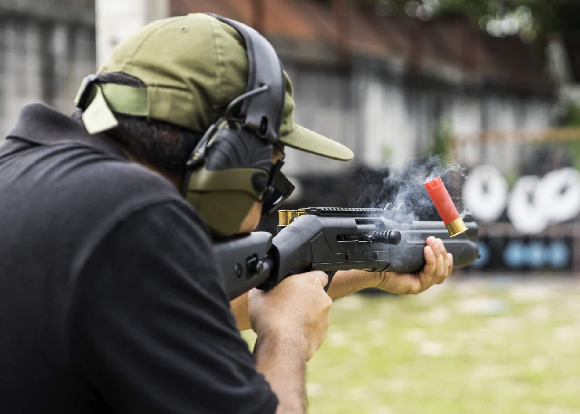 man shooting shotgun down range with headset